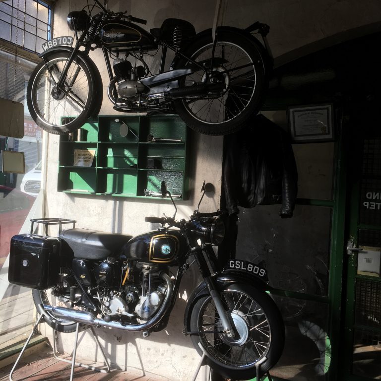 An Excelsior 98cc Motorcycle flying over an AJS 500